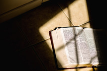 a Bible lying in sunlight on the floor 
