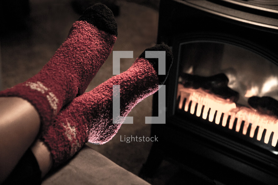 Feet in Red Woolen Christmas Socks by Fireplace