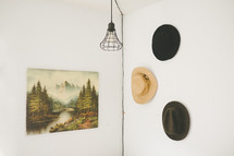 a rustic wire lamp and hats hanging on a wall 