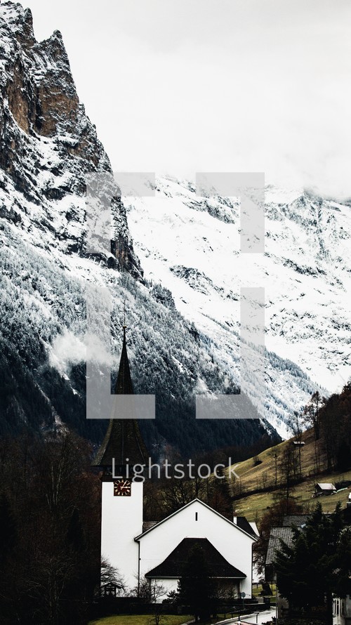A white chapel in Lauterbrunnen, Switzerland sitting in a valley between snowy mountains
