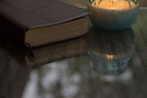 candle and Bible on a glass table top