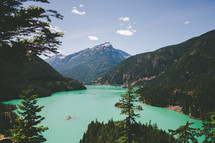A green lake surrounded by mountains and forest.