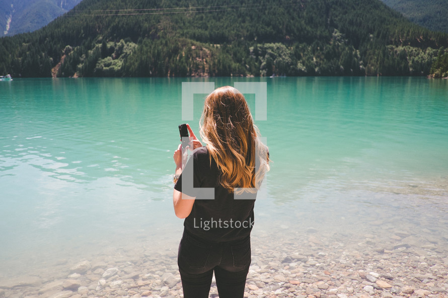 a woman taking a picture of Diablo lake with her cellphone 