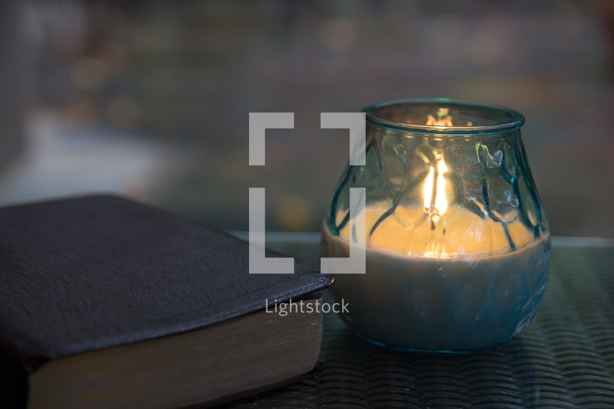 Bible and candle on glass table top 