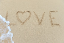 Love written in the sand at the beach.