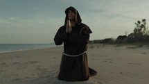 Monk Kneels On The Beach And Starts Praying