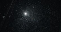 Slow motion snow at night in front of city street light, Snowflakes falling in slow motion during winter snow storm at nighttime.
