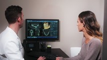 a dentist with his patient going over dental scans in a dental exam room 