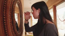 a woman putting on makeup in a mirror 