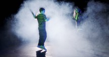 Two young female dancers performing hip hop dance in slow motion with light and smoke background