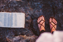 open Bible and feet in sandals 