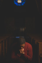 a man kneeling in prayer in the aisle of a Church 