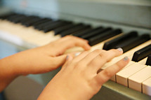 child's hands on a piano 