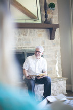 Smiling man sitting on a fireplace hearth during a Bible study.