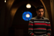 a latino man praying in a church 