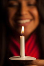 a woman holding a candle at a Christmas Eve service 