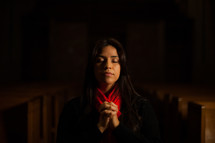 a woman with praying hands in the aisle of a church 