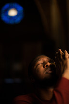 a man with praying hands looking up to God 