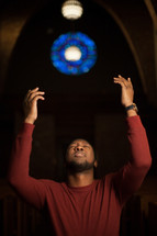 a man standing with raised hands in church 