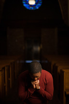 a man kneeling in a church aisle praying 