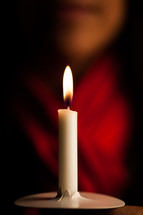 a woman holding a candle at a Christmas Eve service