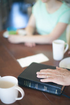 a man's hand on a bible in prayer
