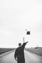 man tossing his graduation cap into the air