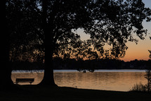 sunset and a park bench by a lake 