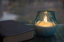 Bible and candle on glass table top 