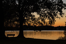 sunset and a park bench near a lake