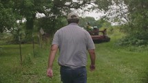 a man walking towards a bailing tractor 