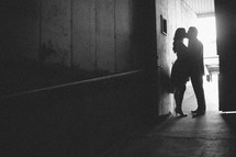 man and woman kissing in a doorway