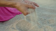 Hands of a girl touching sand on the beach near the ocean