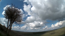 Time lapse of clouds over rural landscape with green hills