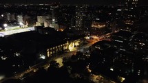 Aerial push-in shot of dynamic downtown Toronto at night. View around the illuminated Queen's Park Avenue . Drone flying over old architecture within the financial district with moderate traffic.