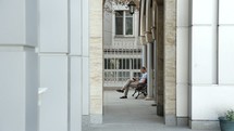a man sitting on a bench in an alley reading a Bible outdoors 