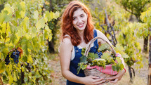 Young girl with basket of grapes walks through the vineyards