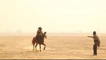 man riding a horse in the desert 
