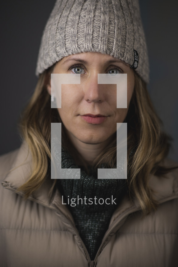 Portrait of a beautiful blonde woman with blue eyes, a beanie, and a puffer