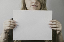 woman holding a blank piece of paper 