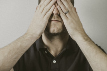 man covering his face with his hands 