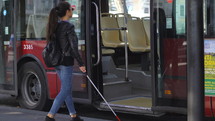 a blind woman getting on a city bus 