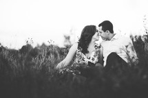 a couple kissing sitting in the grass