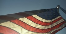 USA, United States American flag flying, blowing in wind on 4th of July in slow motion.