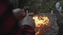 a man scrapping tinder to start a fire in a forest 