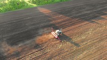 Aerial view of a tractor that irrigates the sown field through a special installation. Tractor plowing and cultivating a farm field. Harvesting the wheat field with agricultural machinery.