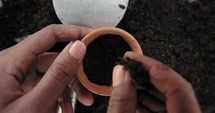 a woman putting potting soil into clay pots 