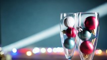 Glasses filled with Christmas balls under flashing lights 
