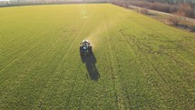 Tractor spreading fertilizers in green field