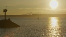 Pan across water in front of Olympic mountain range with sailboats during sunset